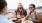 young friends on a balcony overlooking the pier, toasting drinks around a table of food